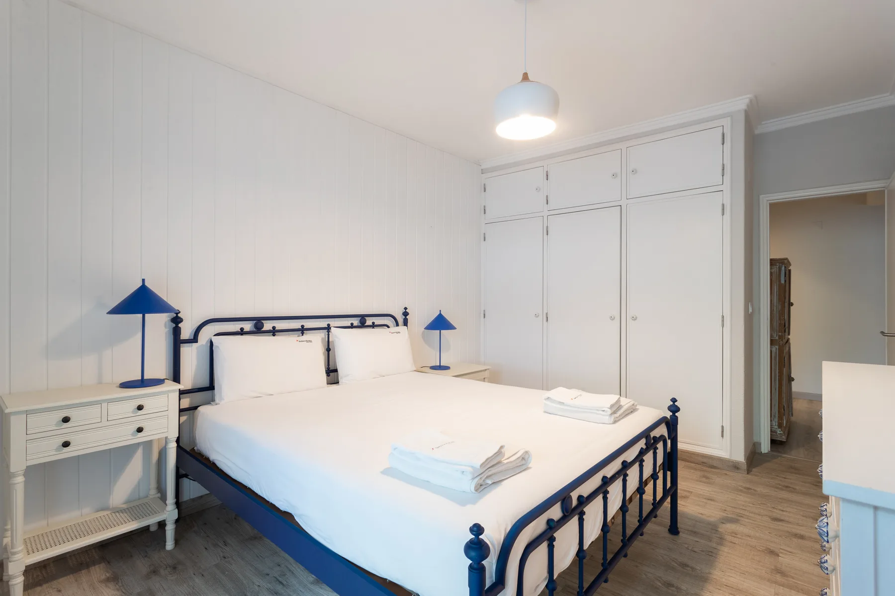 A bedroom with a large bed, matching bedside lamps, and built-in wardrobes.