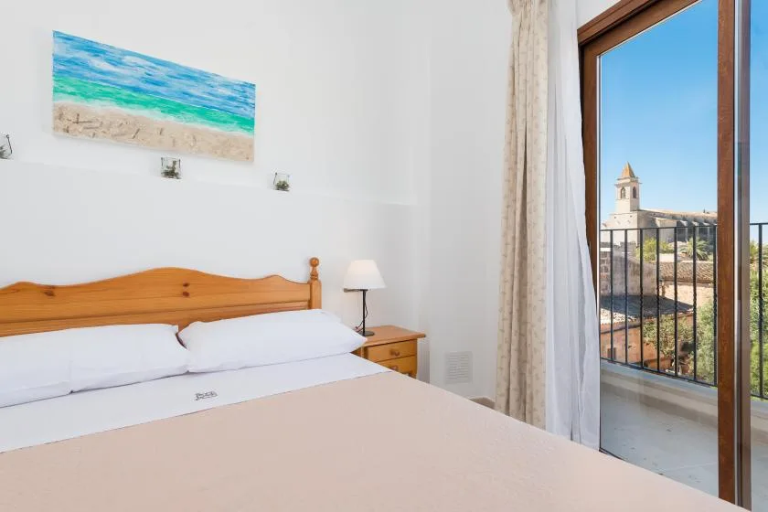 A bedroom with a wooden bed, white bedding, and a balcony view.