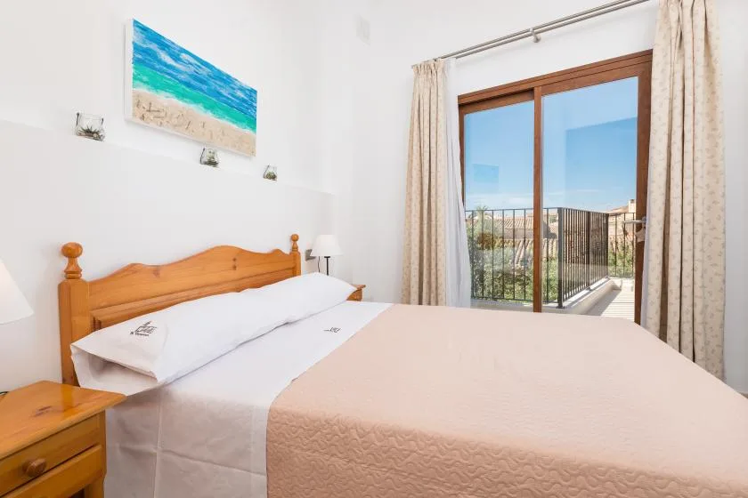 A bedroom with a bed beside glass doors opening onto a balcony.