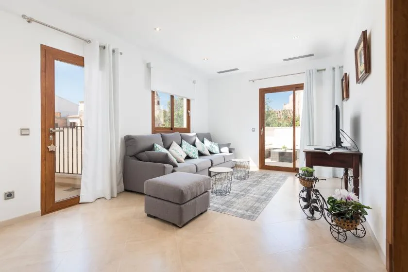 A bright living room with seating, a rug, and glass doors opening to a balcony.