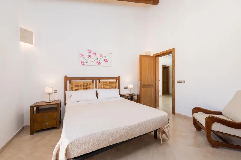 A bedroom with a double bed, bedside tables, and an open doorway.