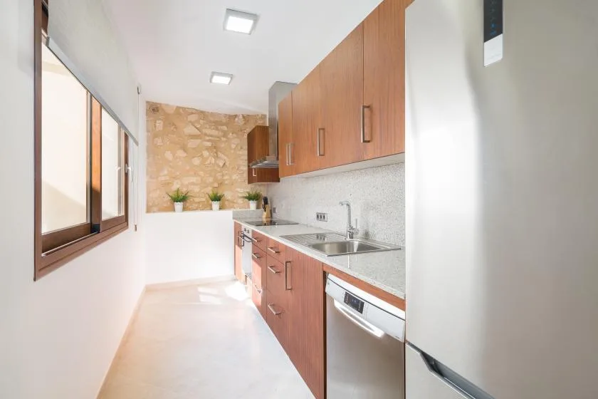A narrow kitchen with wooden cabinets, a countertop, and a sink.