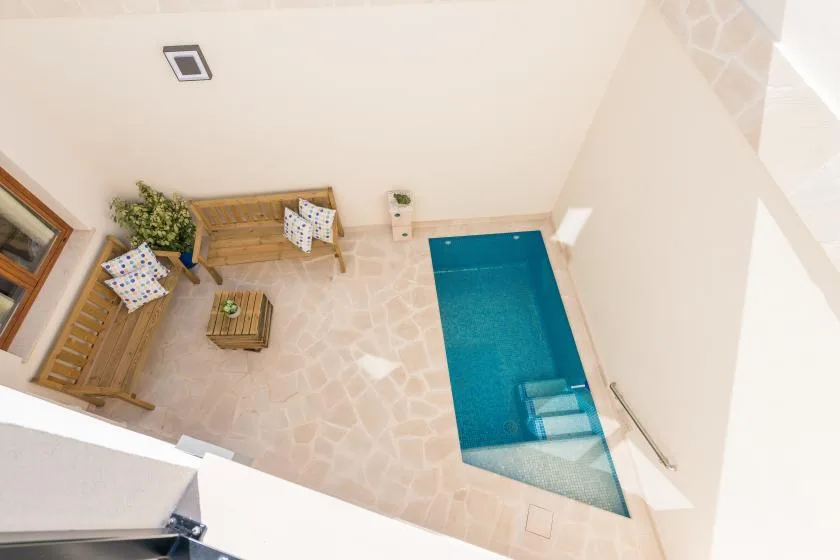 A small indoor pool beside a seating area with a wooden table.