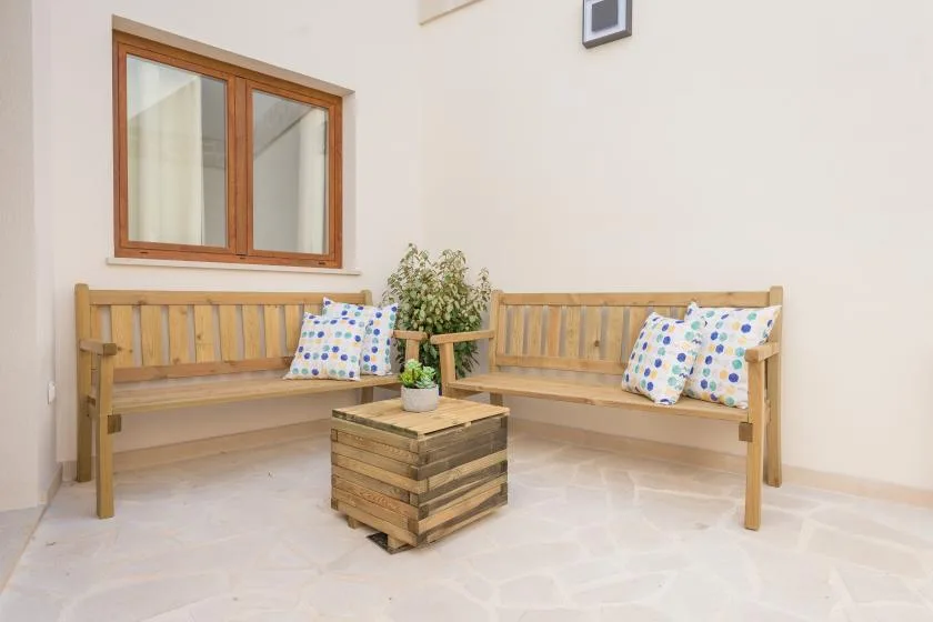 A bright patio seating area with wooden benches and a small table.