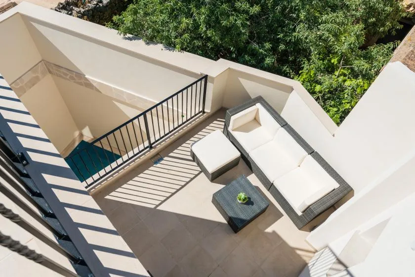 A sunlit outdoor seating area with a white lounge sofa and low table.