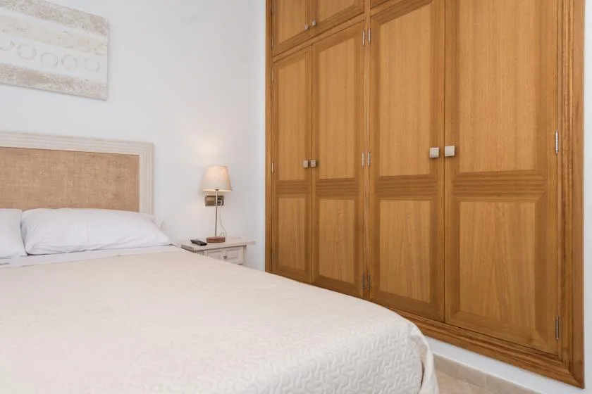 A bedroom with a bed beside a large wooden wardrobe.