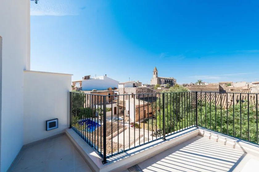 A sunny balcony overlooks nearby rooftops and a church tower.
