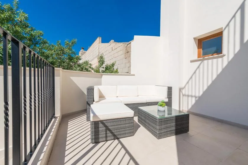A sunny outdoor seating area with a cushioned sectional and glass-topped table.