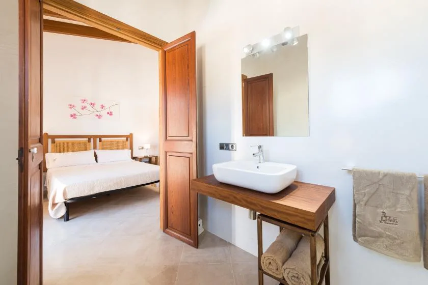 A bedroom with a bed beside a washbasin and mirror.