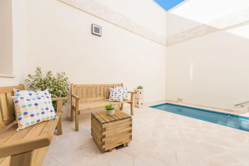A bright indoor pool area with wooden seating and a small table.