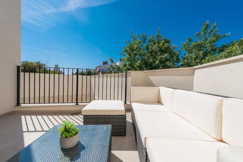 An outdoor terrace with white seating and a low table beneath a blue sky.