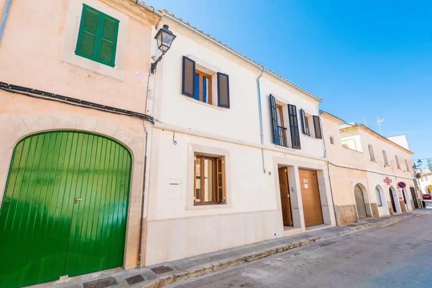 A row of pale stucco buildings with green shutters and a large green garage door.