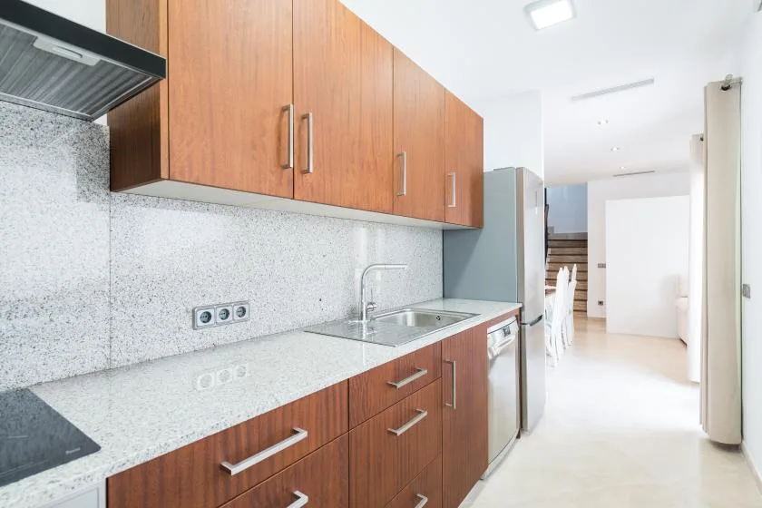 A bright kitchen with wooden cabinets and a countertop sink.