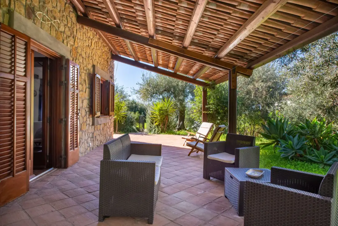 A covered outdoor patio with seating and views of the garden.