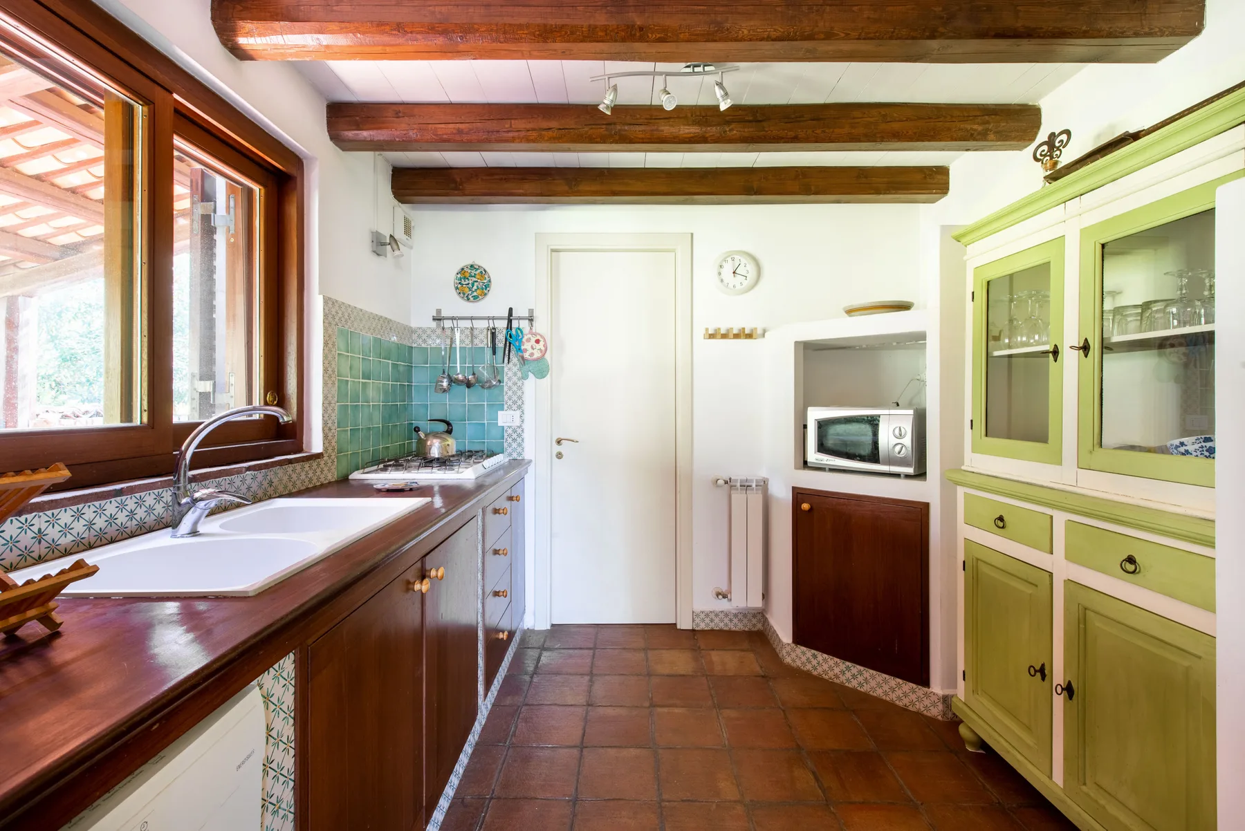 A kitchen with wooden counters, a sink, and pale green cabinets.