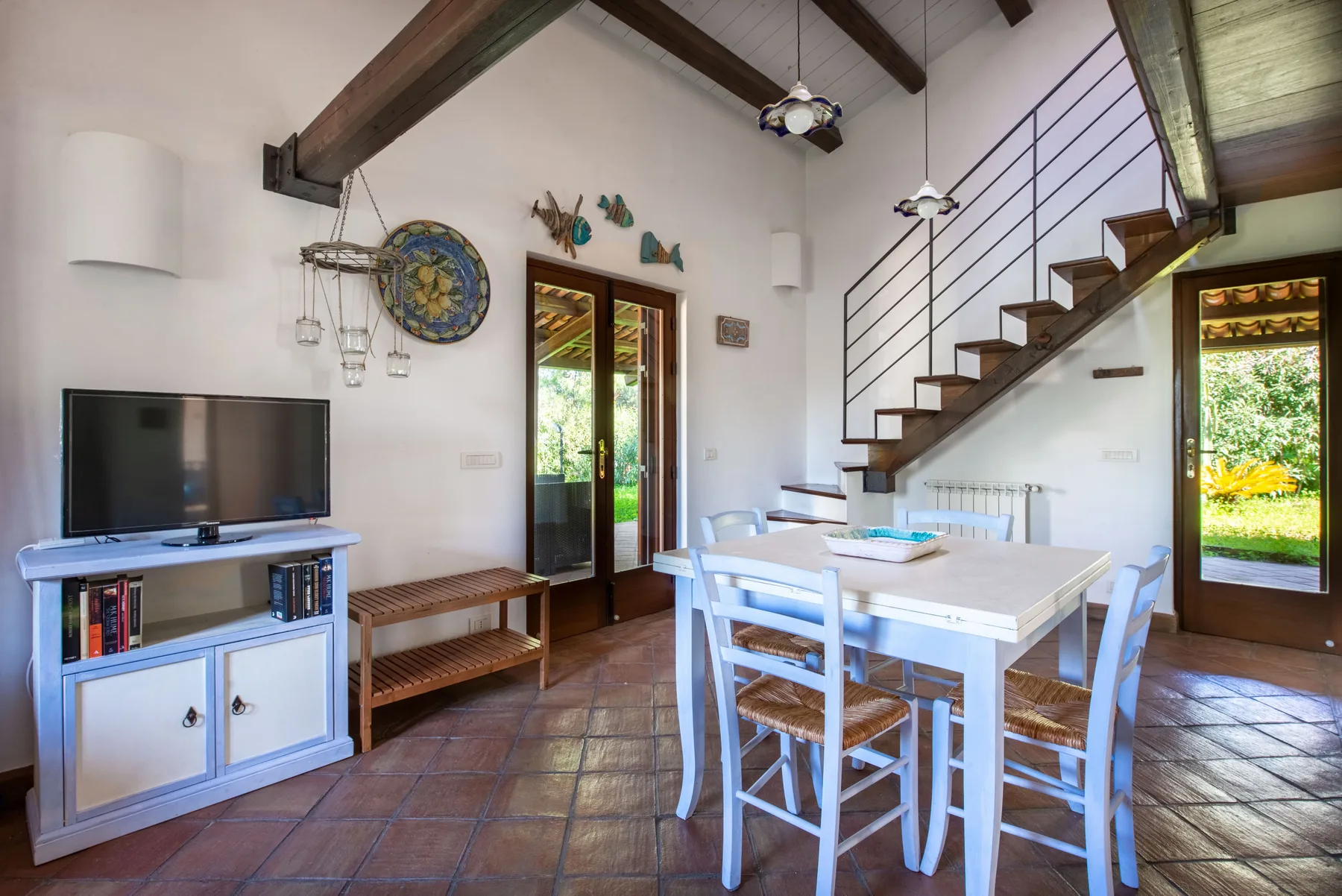 A dining area with a table and chairs beside a staircase and glass doors.