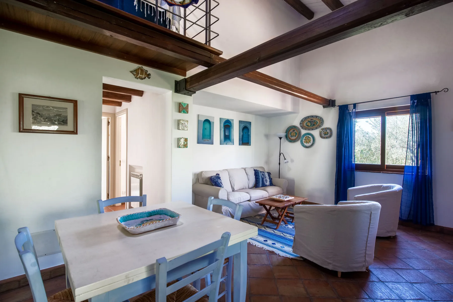 A dining and living area with a table, seating, and blue curtains by the window.