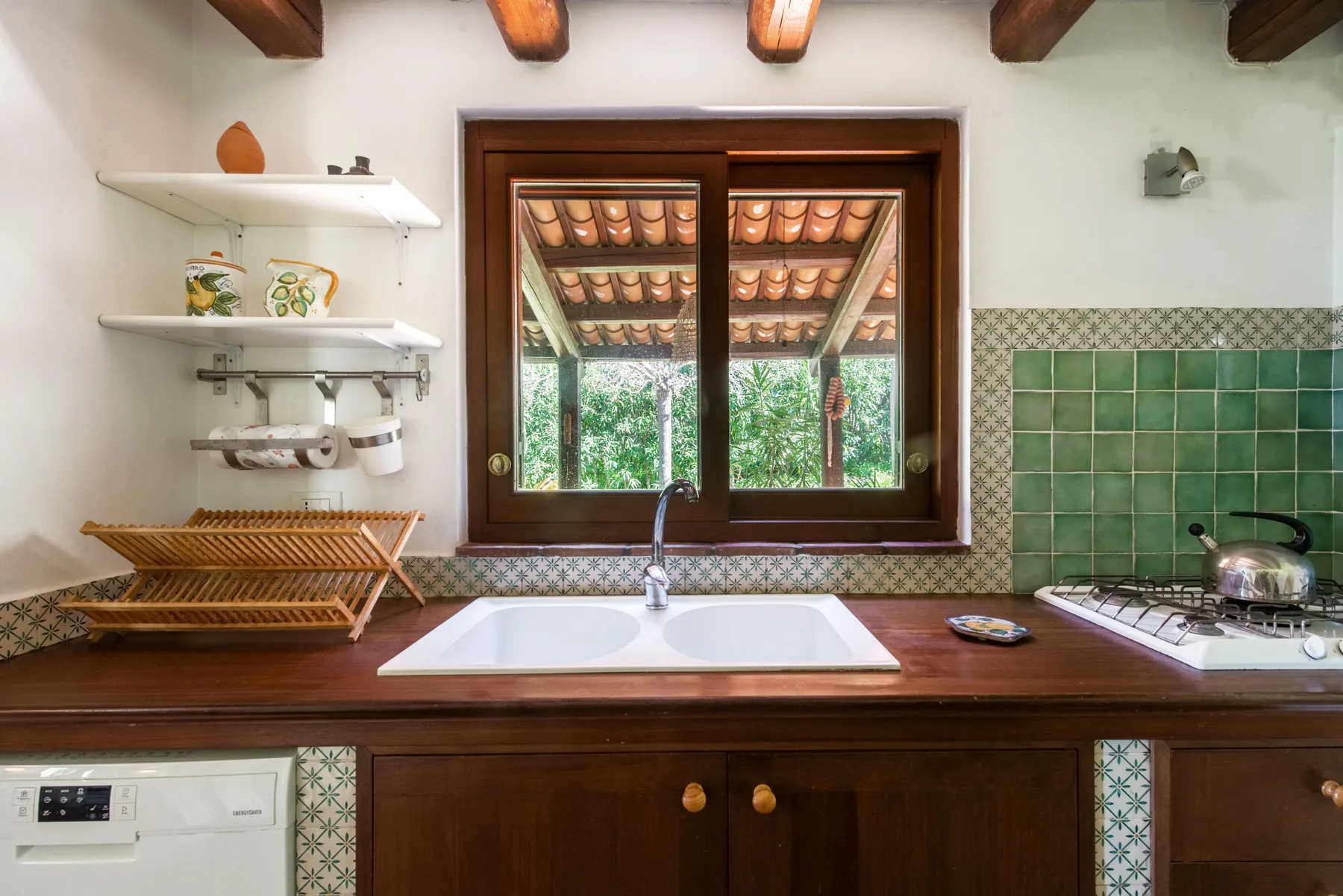 A kitchen with a double sink beneath a window and a stovetop.