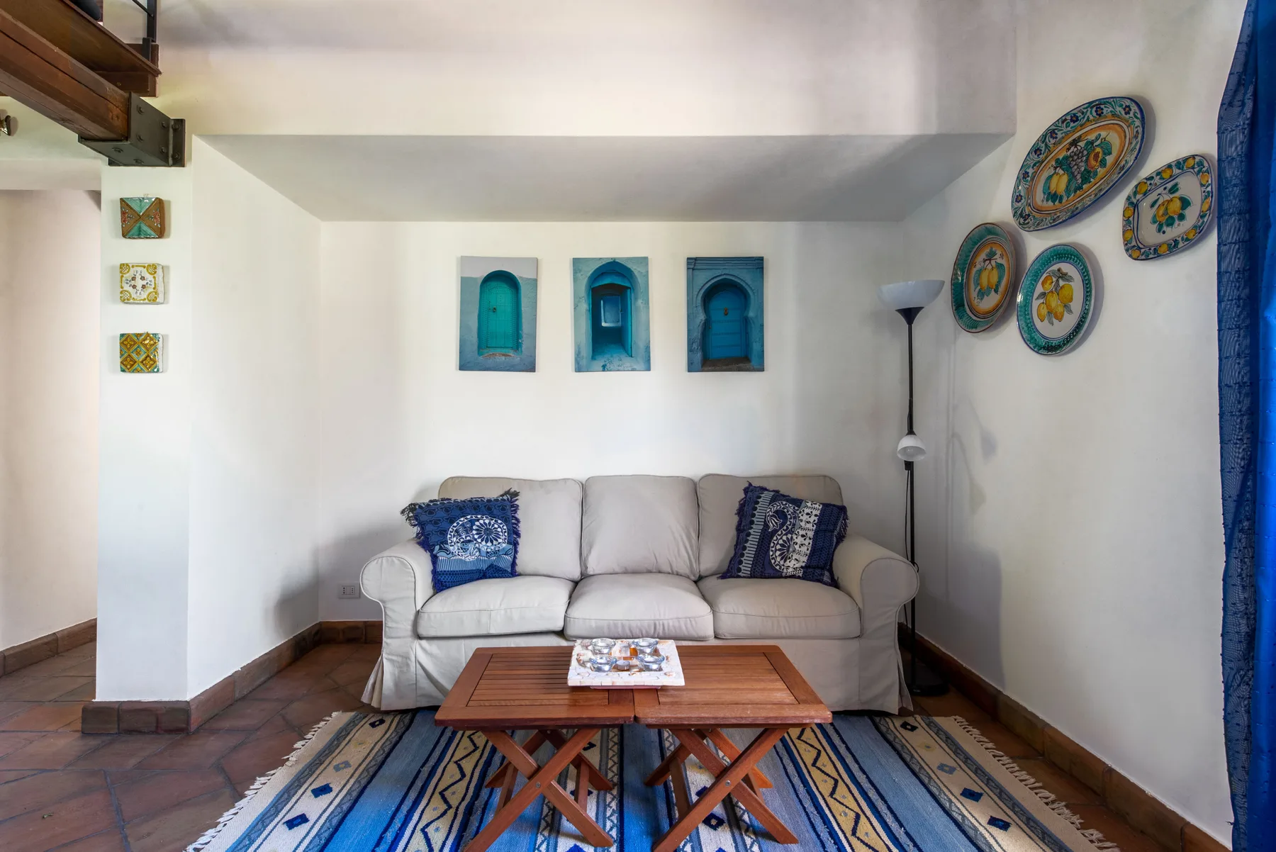 A living room with light-colored seating, decorative wall niches, and a patterned rug.