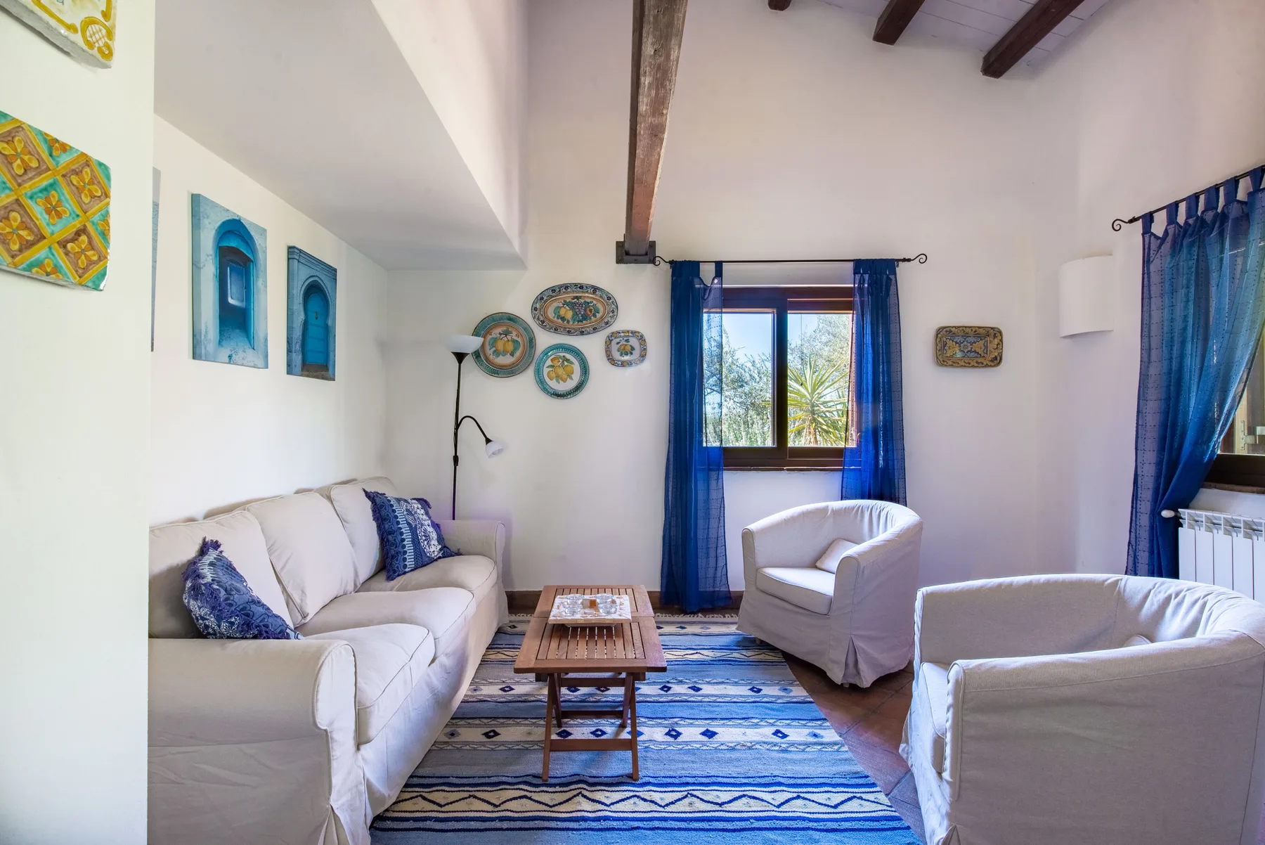 A bright living room with seating, a wooden coffee table, and blue curtains.