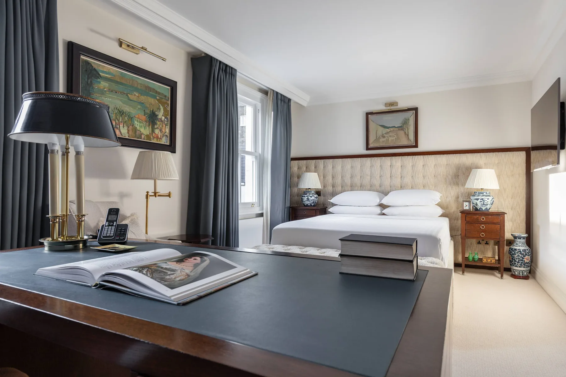 A bedroom with a large bed, bedside tables, and a writing desk.