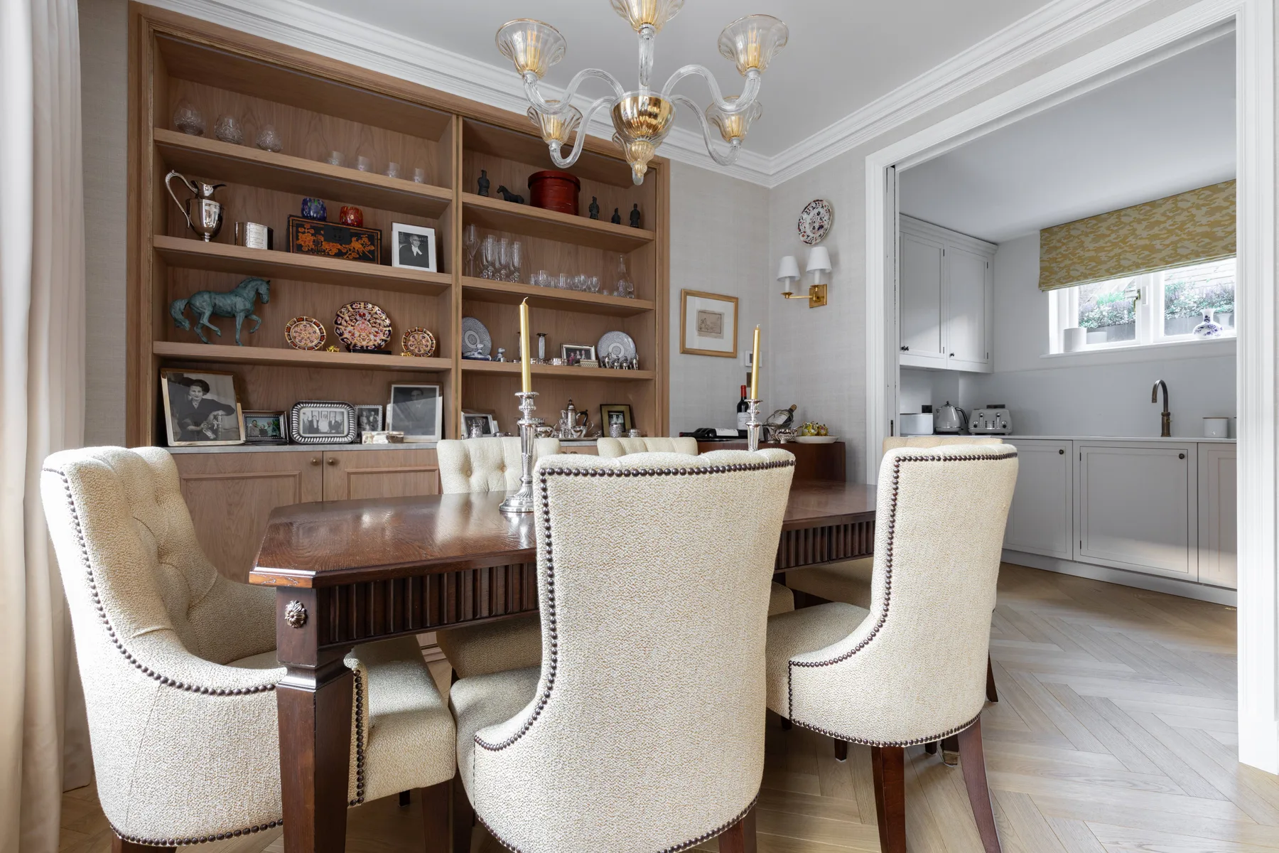 A dining area with a wooden table, upholstered seating, and built-in shelves.