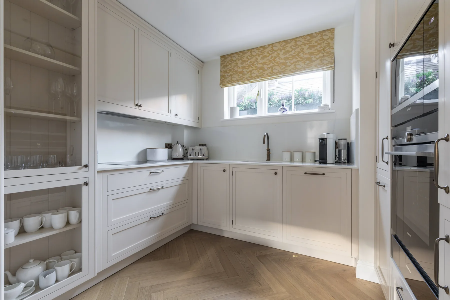 A bright kitchen with white cabinetry, a countertop, and a window.