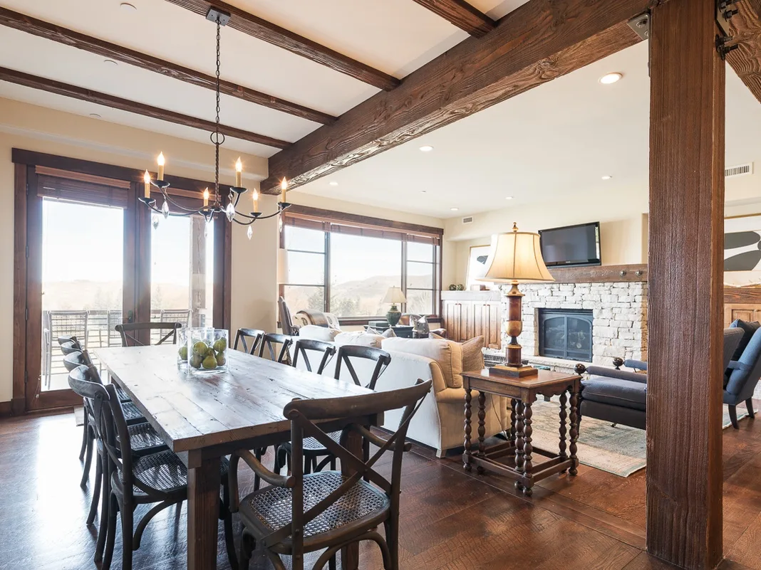 El comedor se abre a una sala de estar con chimenea de piedra y ventanales.