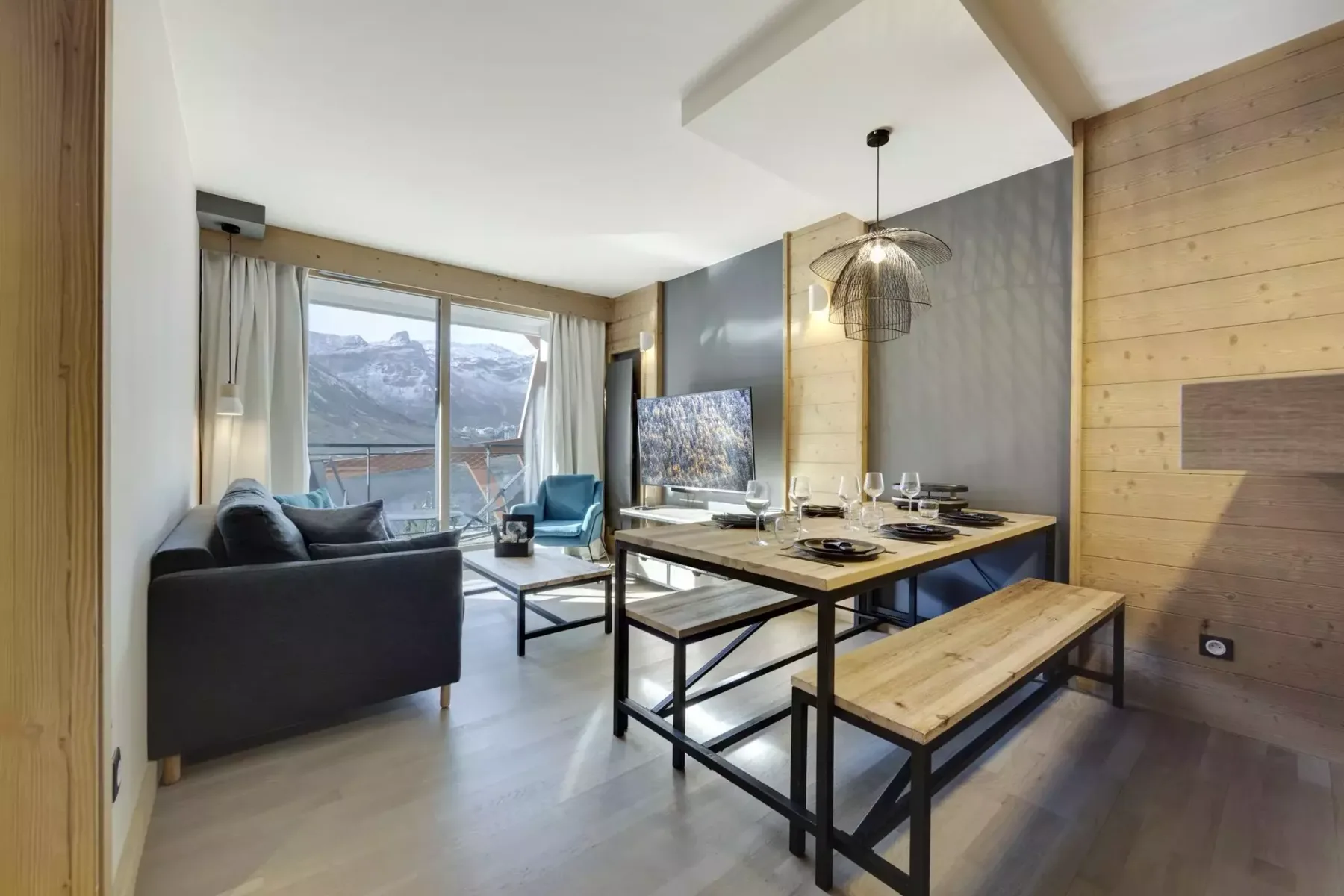 A living and dining area with a table, seating, and large windows overlooking mountains.