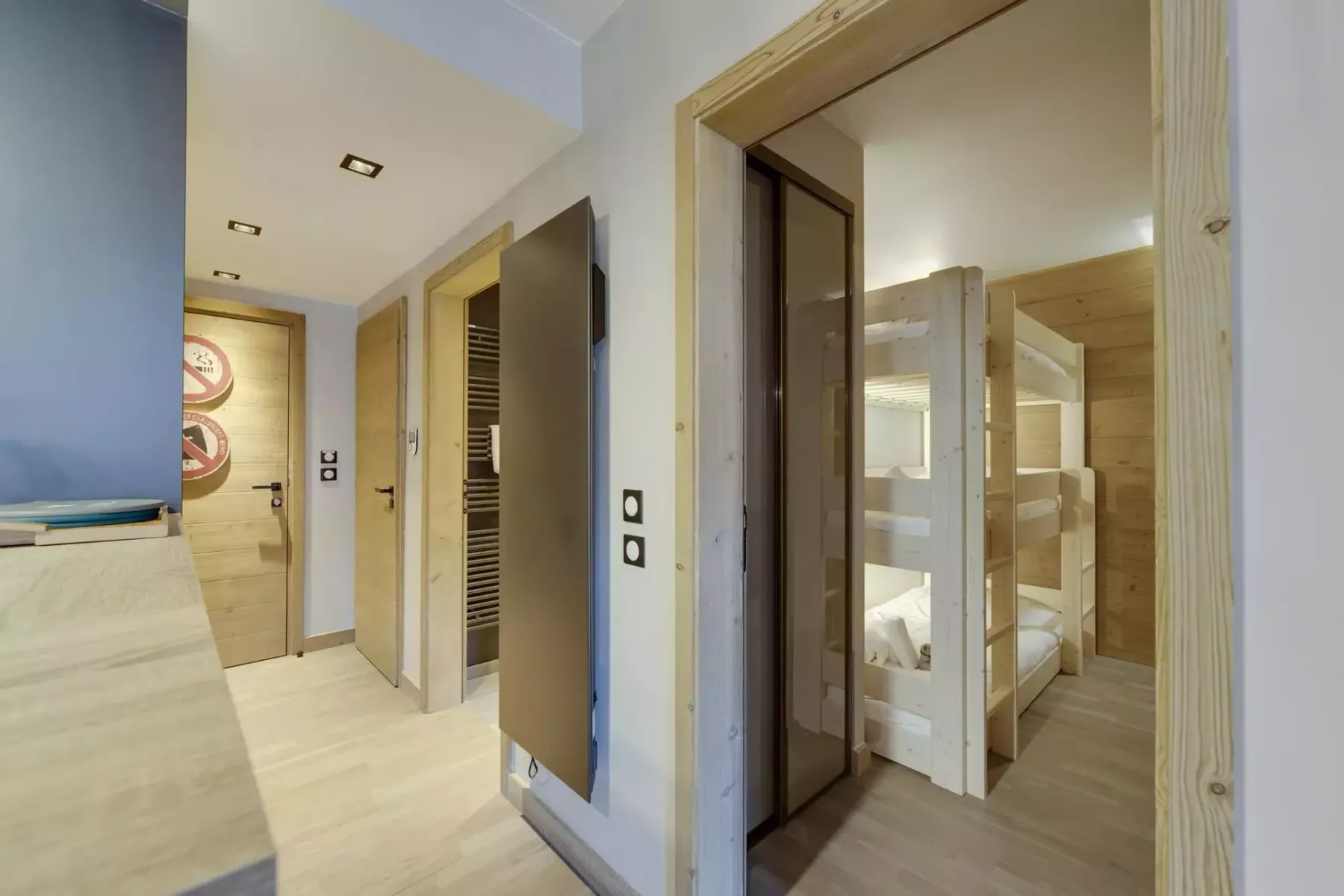 A hallway opens onto a bunk sleeping area, with light wood finishes throughout.