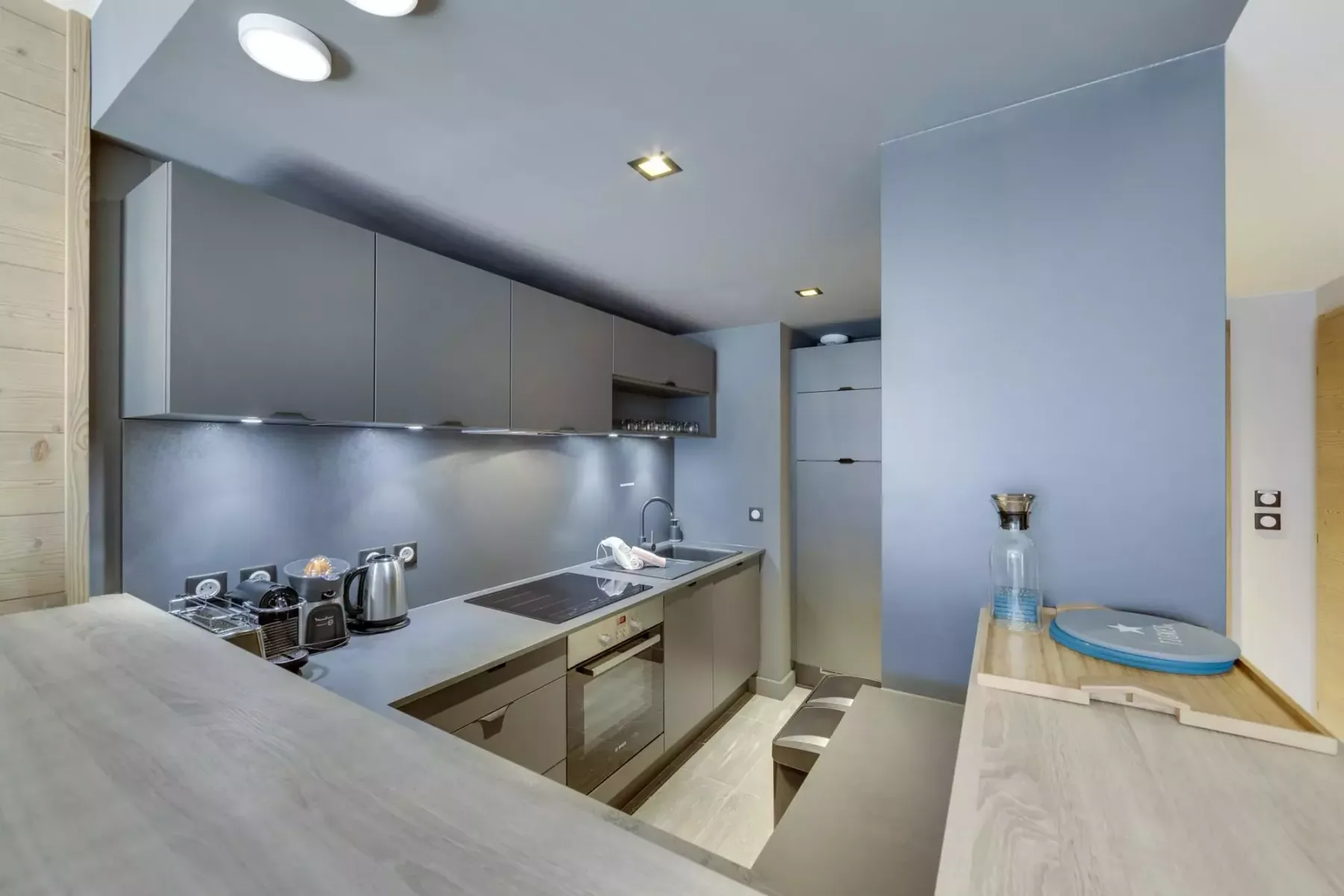 A modern kitchen with gray cabinets, a cooktop, and a counter.