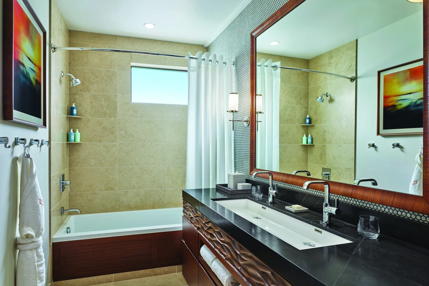 Un baño con bañera, panel de ducha de vidrio y tocador con dos lavabos.