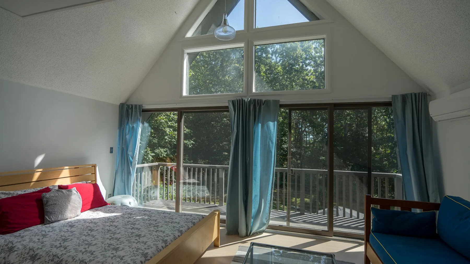 A bright bedroom with a bed and sliding glass doors opening onto a balcony.
