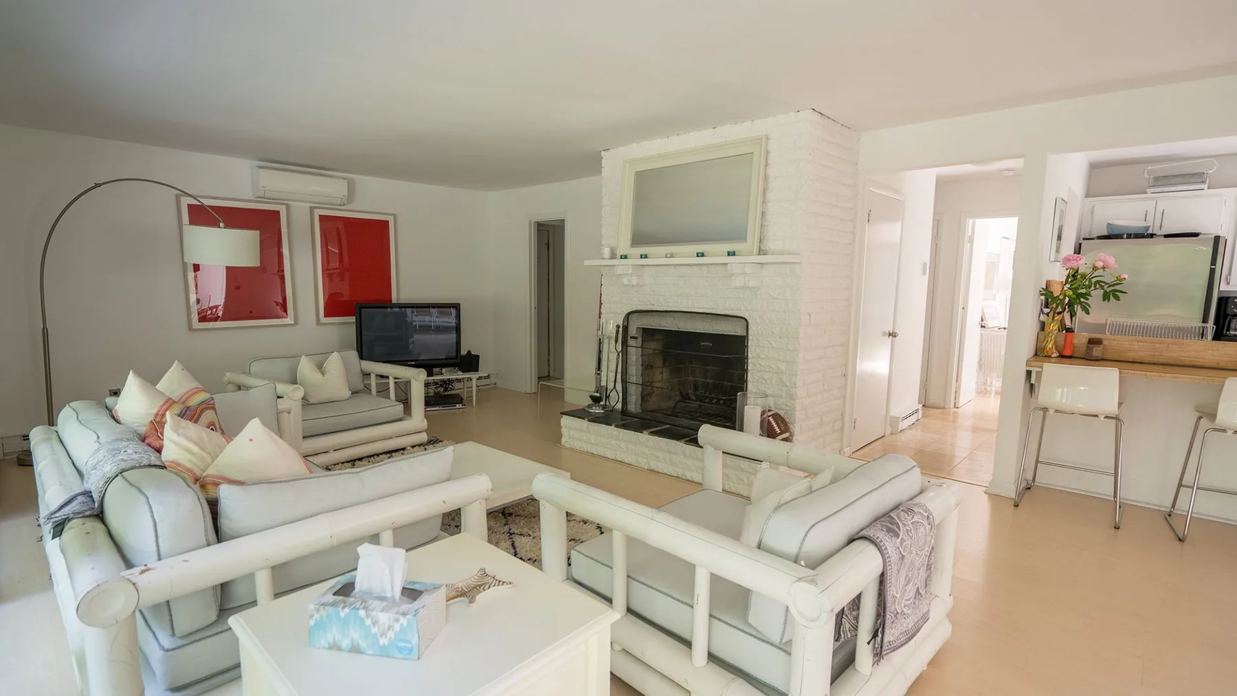 A bright living room with white seating arranged around a fireplace.