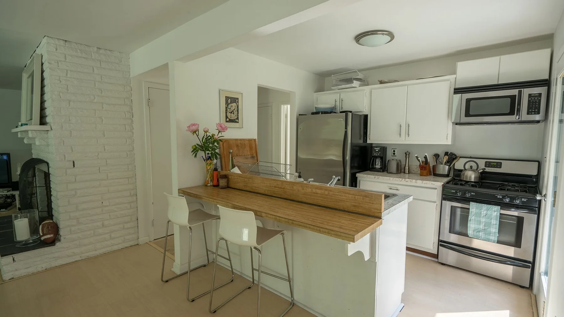 A bright kitchen with a counter, bar seating, and white cabinets.