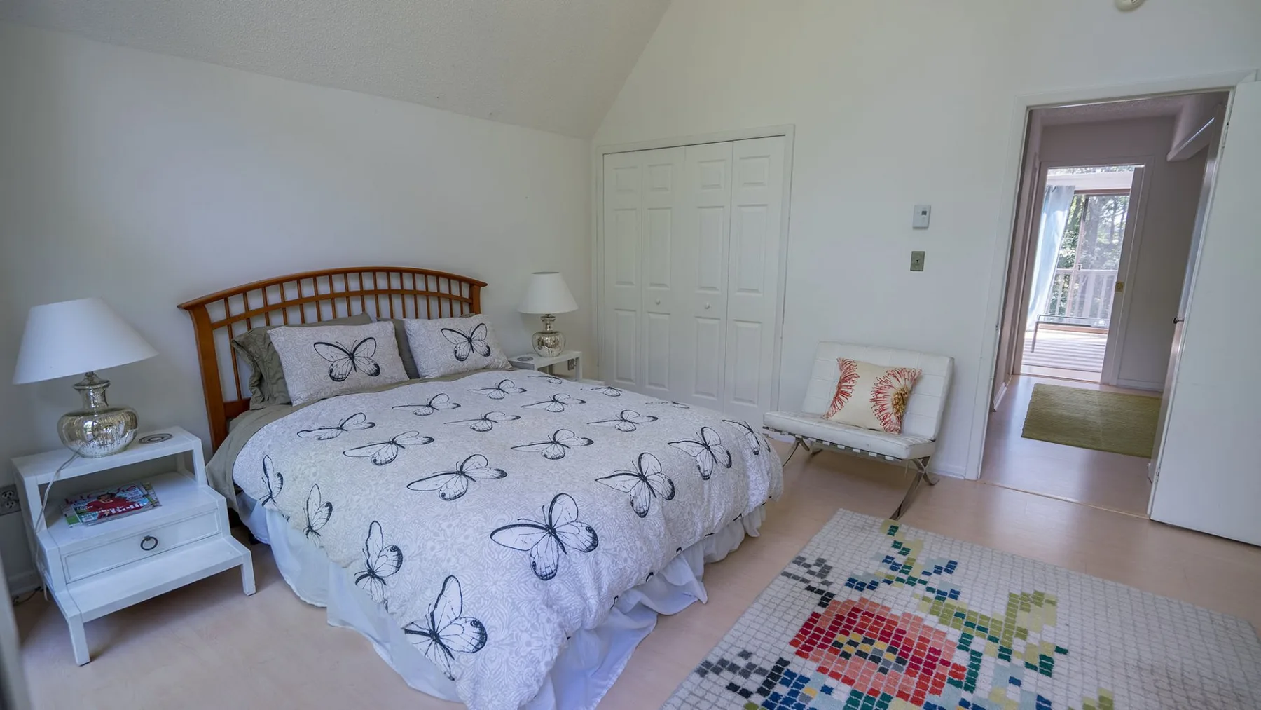 A bedroom with a bed covered in butterfly-patterned bedding and a small seating area.