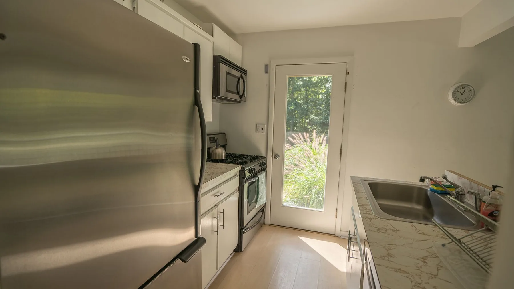 A kitchen with stainless steel appliances, counters, and a glass-paneled exterior door.
