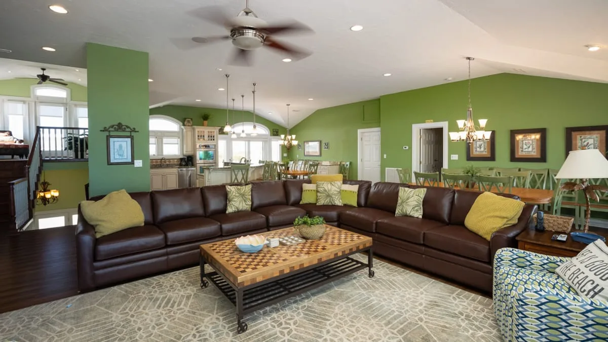 A spacious living room with sectional seating, a coffee table, and green walls.