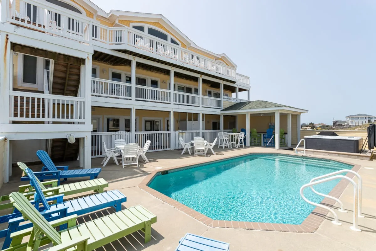 An outdoor pool beside a multi-story building, with lounge seating around the water.