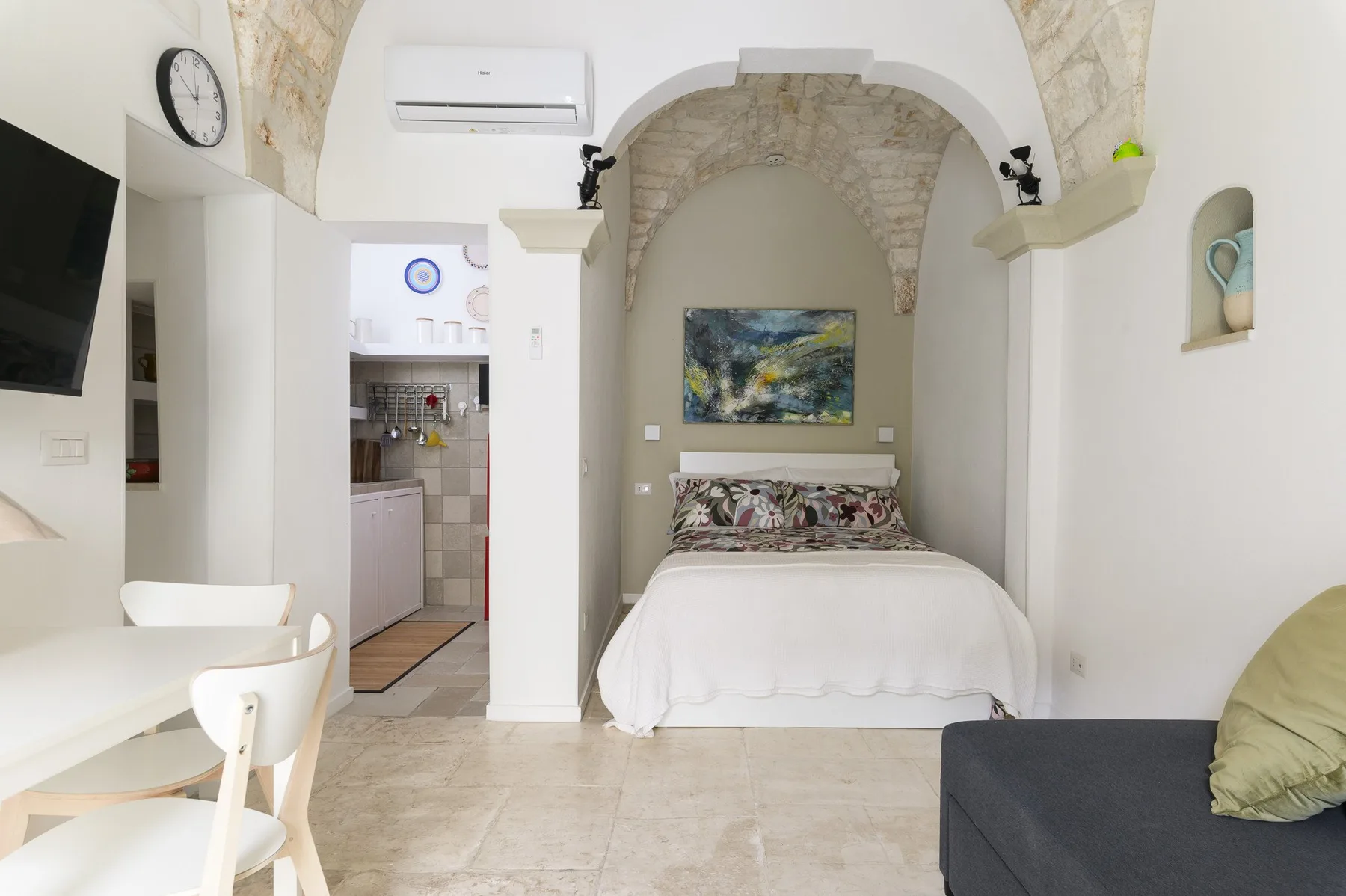 Un dormitorio con una cama bajo un techo arqueado de piedra y una pequeña zona de estar.