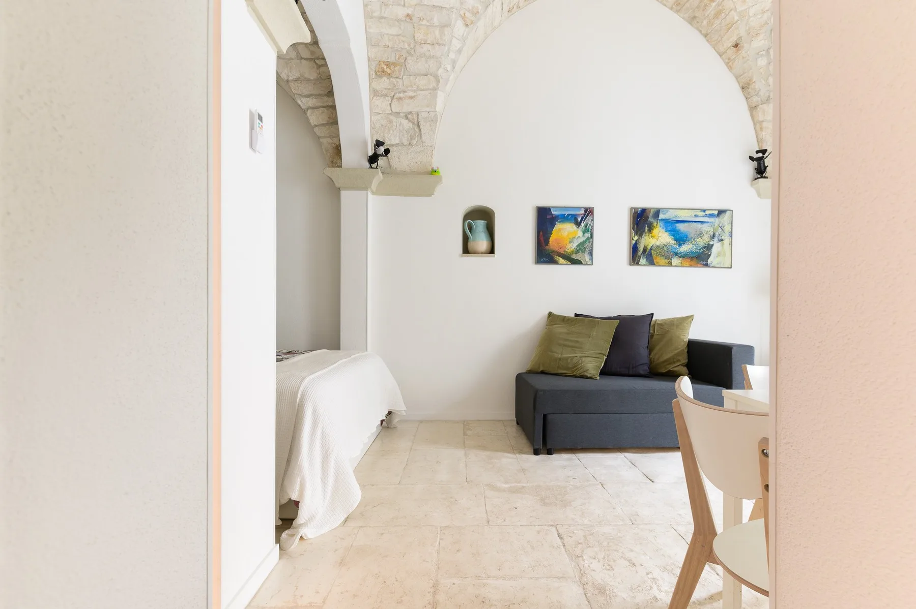 A bright sitting area with a dark sofa beneath a stone arch.