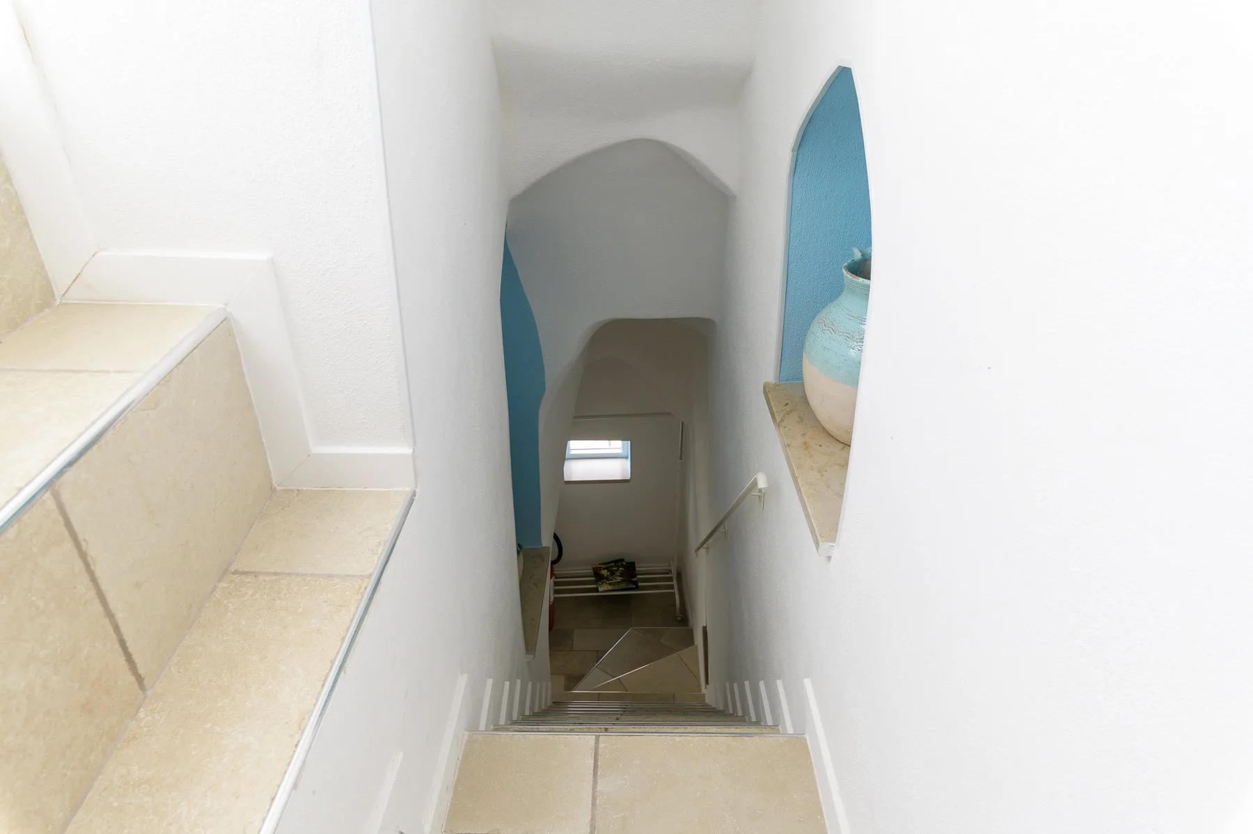 An interior stairway descends beneath an arched opening, with a small window at the bottom.