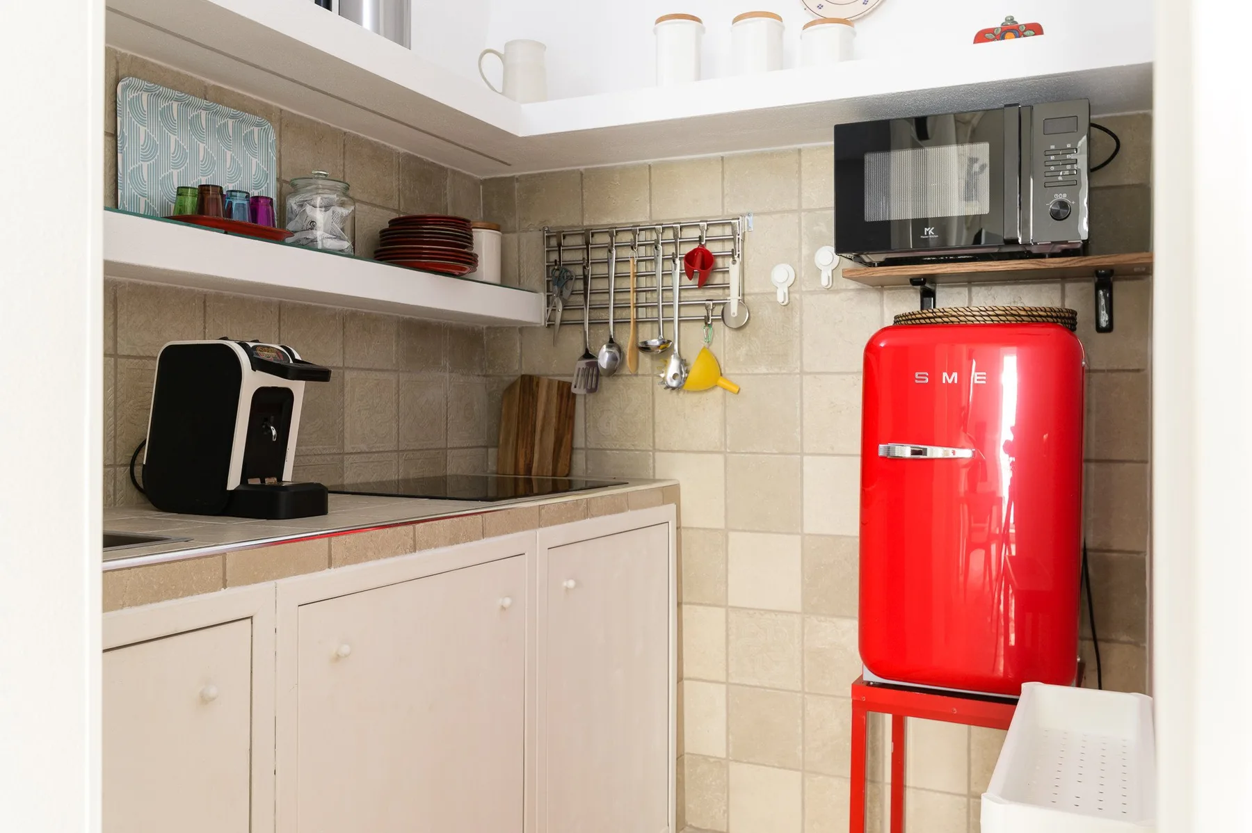 Una cocina compacta con encimera, pequeños electrodomésticos y un refrigerador rojo brillante.