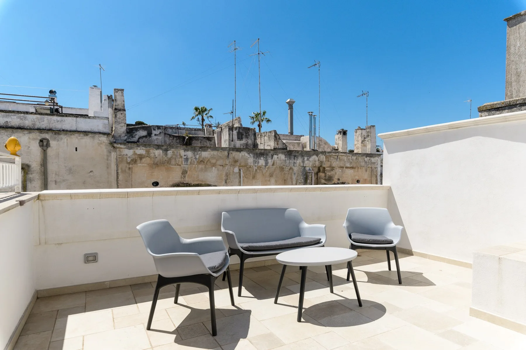 A sunny rooftop terrace with outdoor seating and a small table.