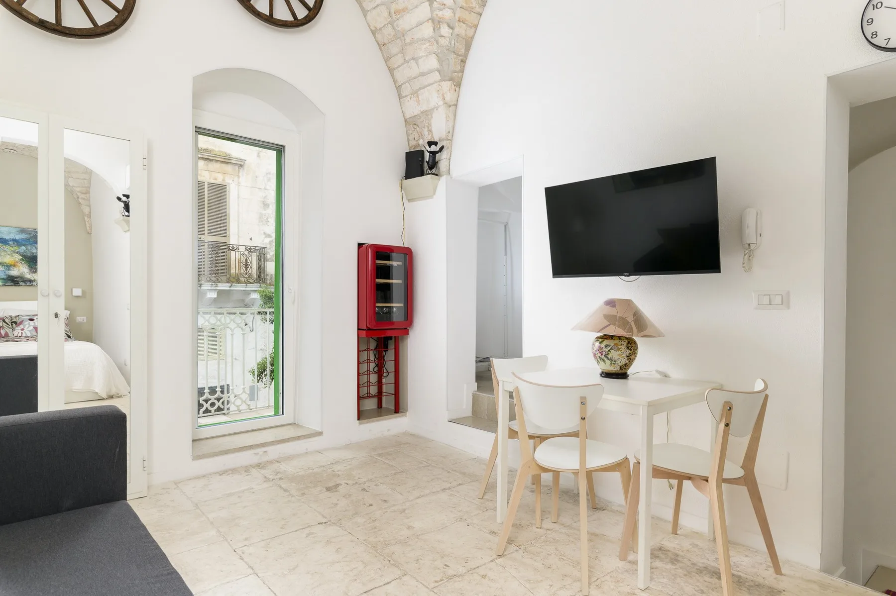 A bright dining area with a table and chairs beneath a wall-mounted television.