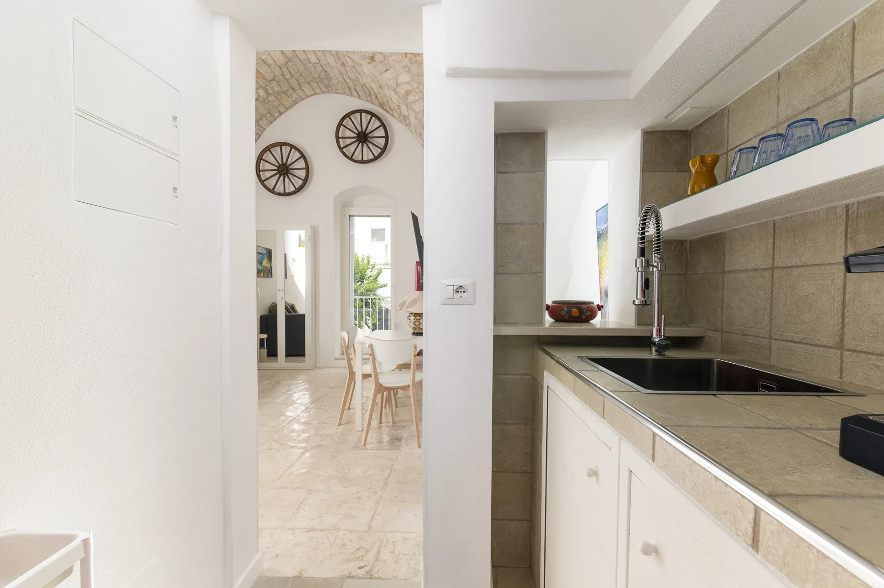 A bright kitchen with a dark sink and a dining area visible beyond the doorway.