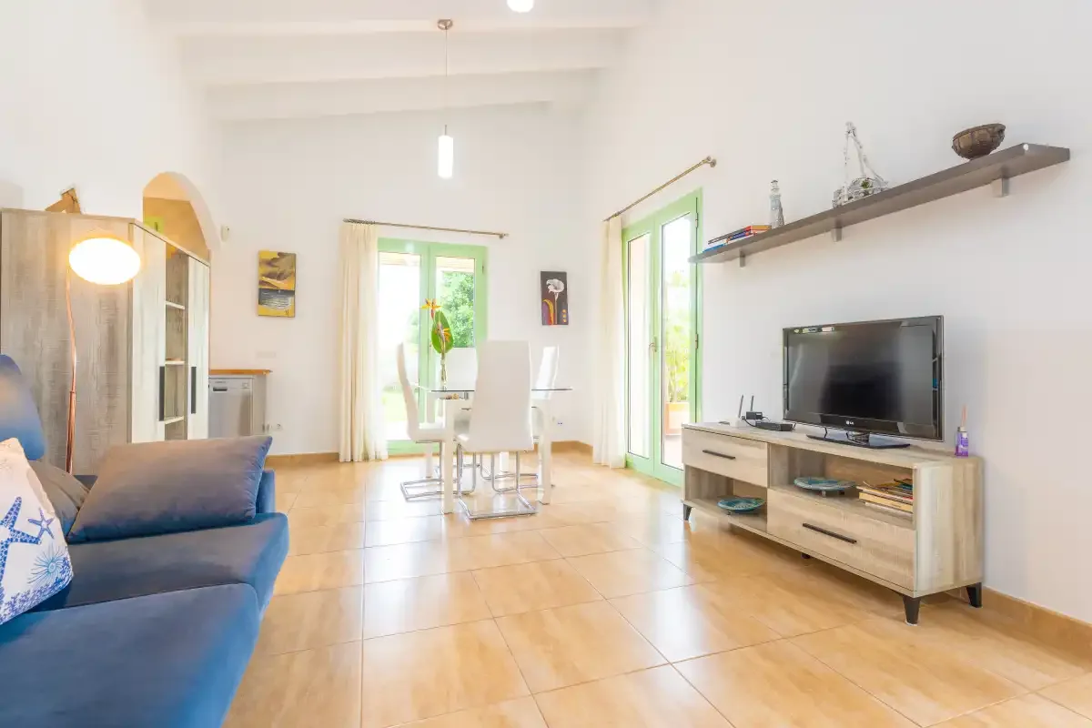 A bright living room with seating, a television, and glass doors opening to a patio.