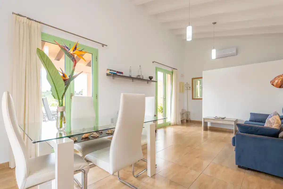A bright living and dining room with a glass table and blue seating.