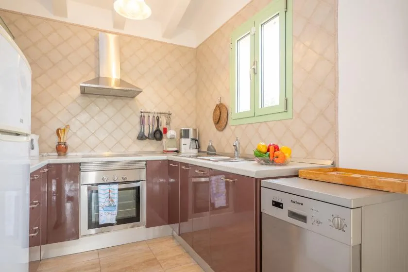 A bright kitchen with brown cabinets, a stainless-steel oven, and a green-framed window.