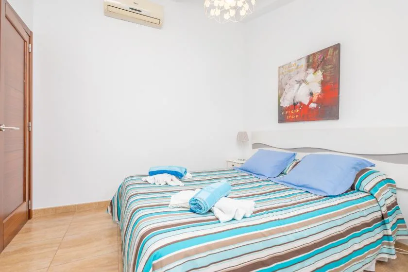 A bedroom with a striped bedspread, blue pillows, and folded towels.